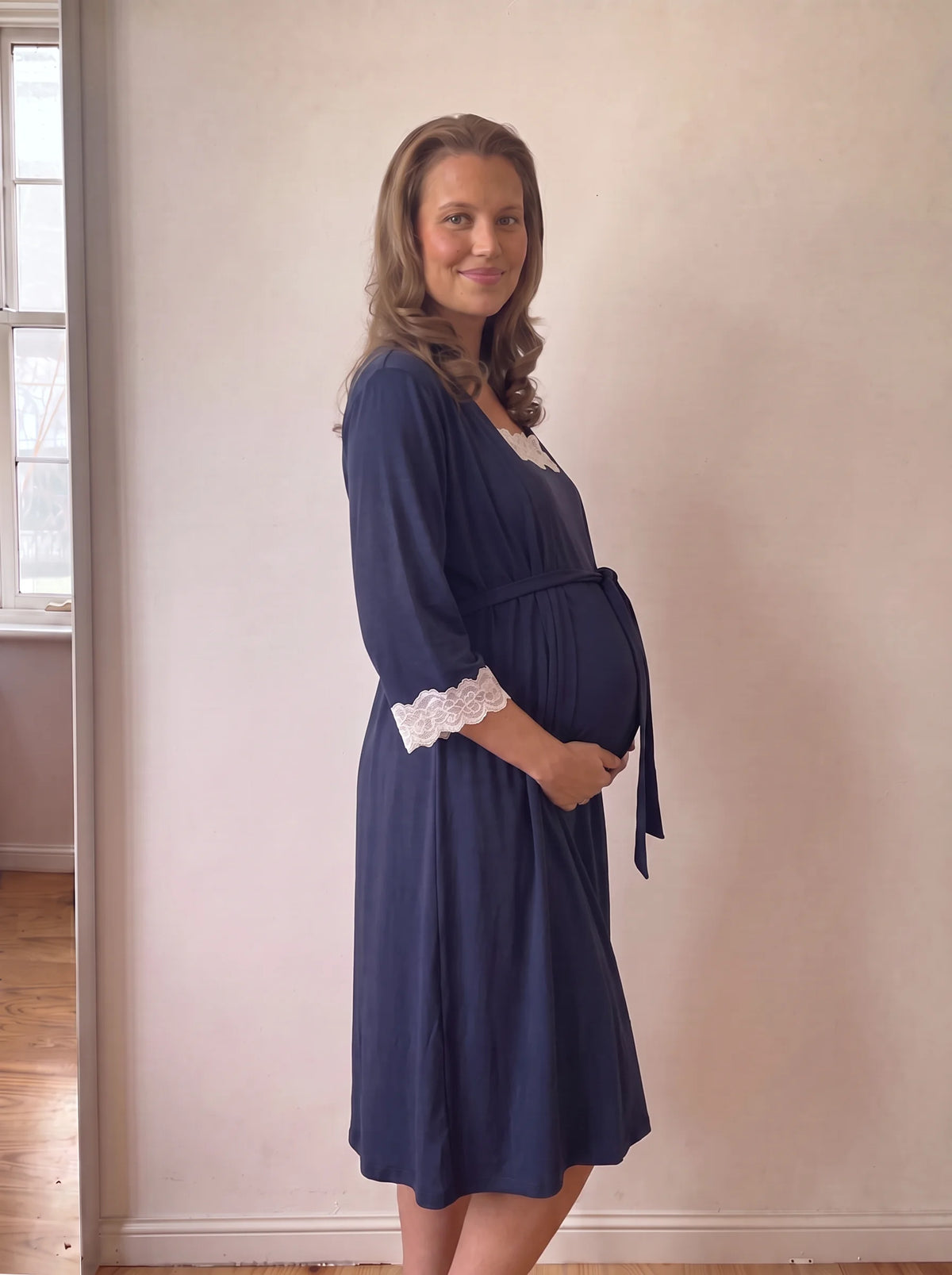 Side view of the navy robe tied over the bump with ivory lace cuffs