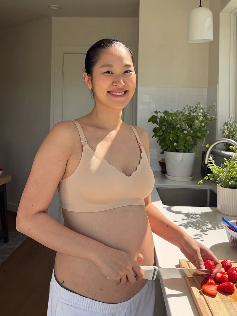 Pregnant mom smiling while slicing strawberries in the Aura Comfort Bra in Skin