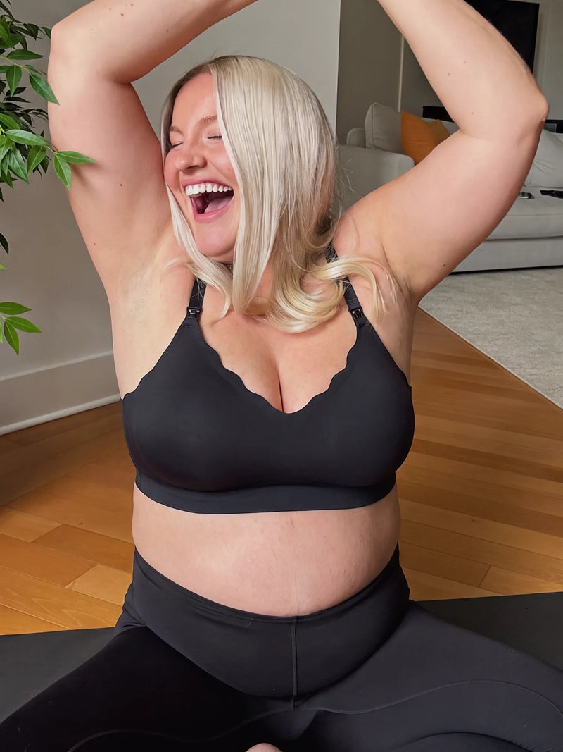 Mom laughing while stretching at home in the Aura Comfort Bra in Black