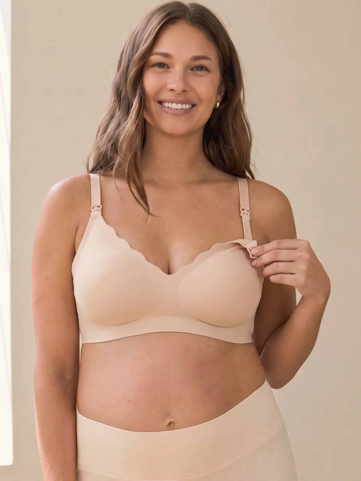 Smiling pregnant mom opening the nursing clip of the Aura Comfort Bra in Skin