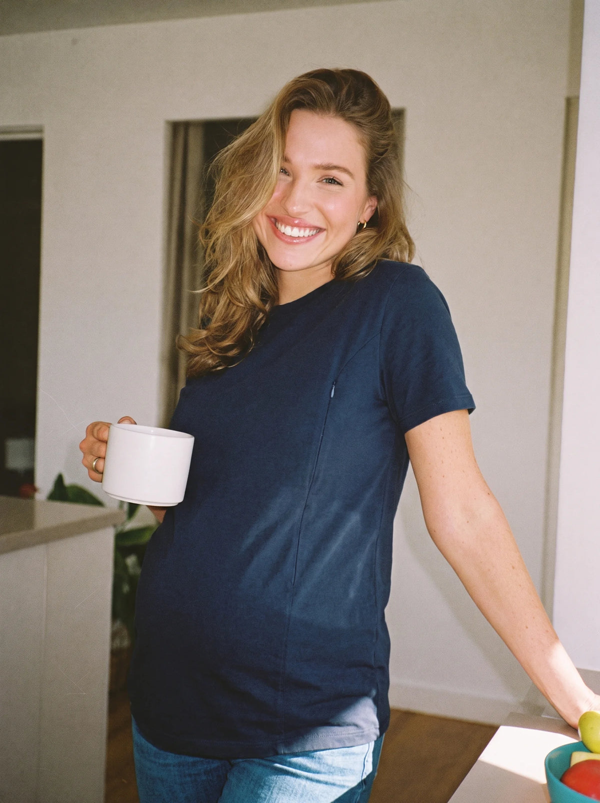 Mom in navy hidden zip nursing tee in the morning at home