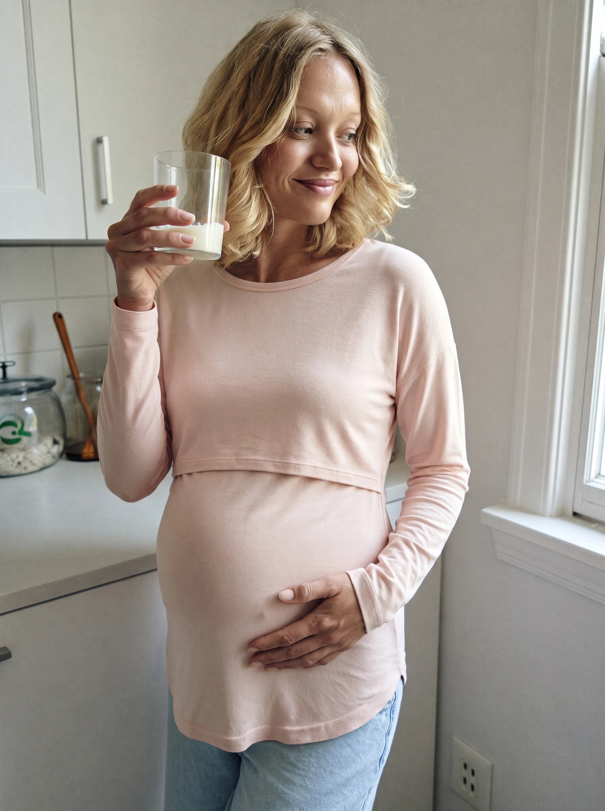 Pregnant woman in the blush pink layered nursing top in a bright kitchen