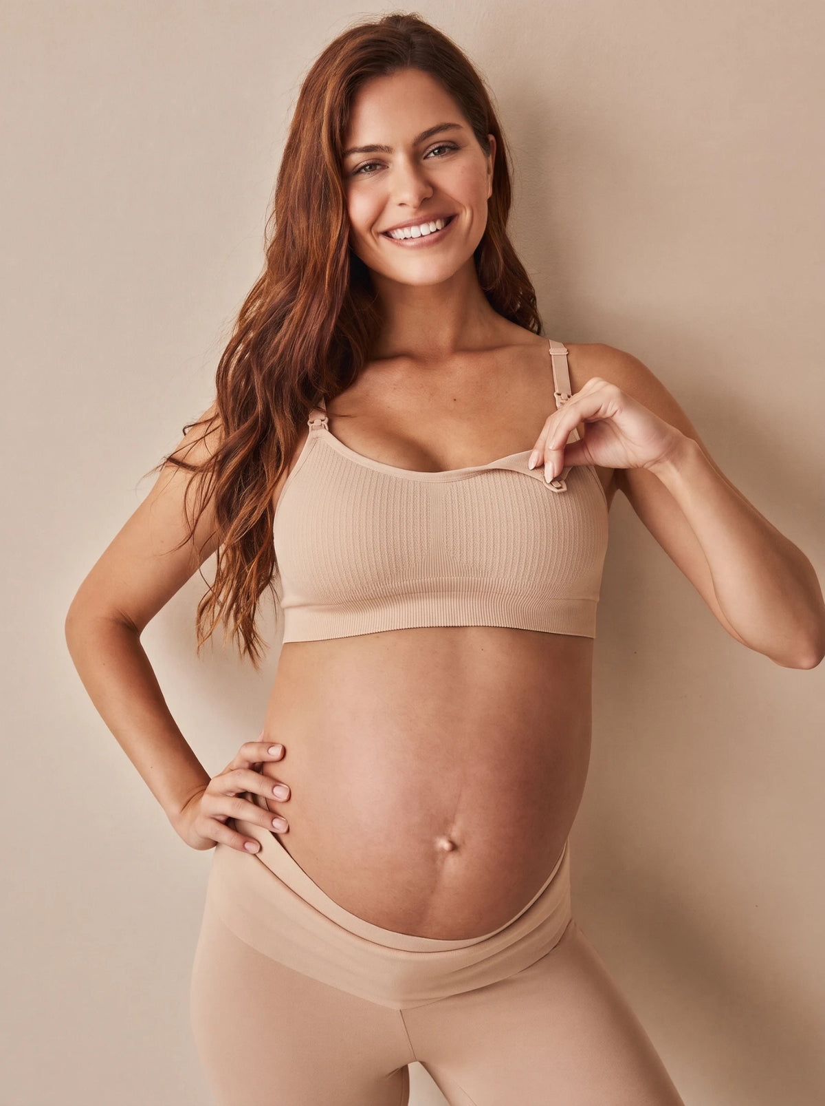 Smiling pregnant mom opening the nursing clip of the Aura Nursing Bra in Skin