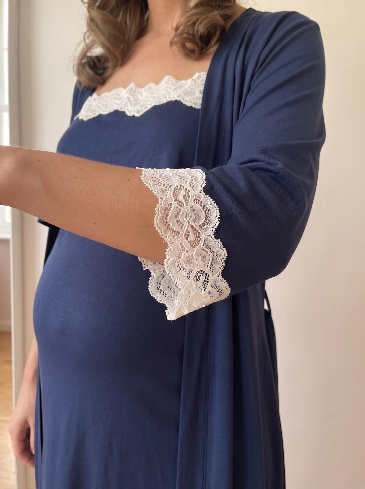Close up of the ivory lace cuff on the navy robe and the lace neckline of the nightgown