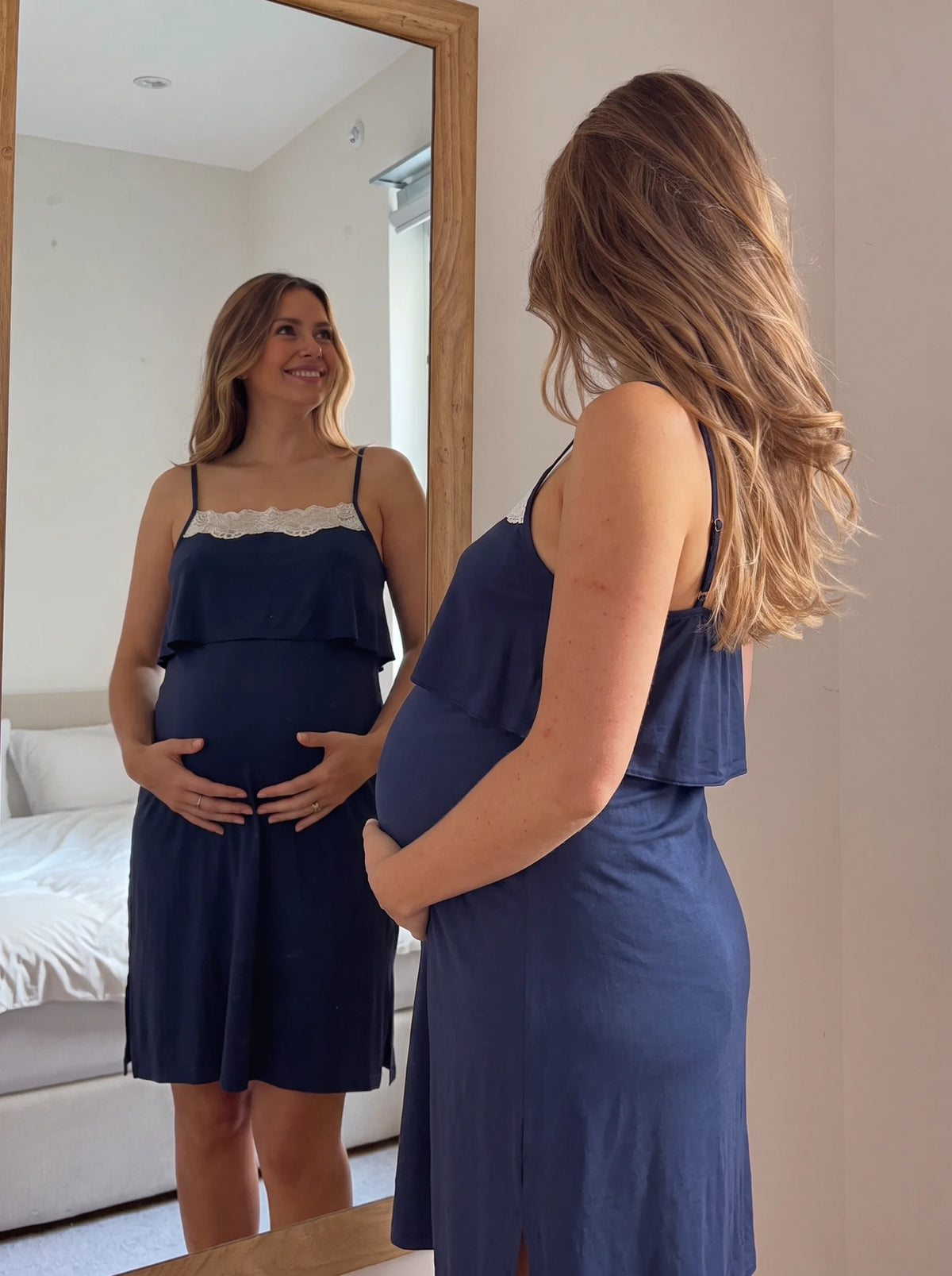 Pregnant mom looking at her bump in the mirror wearing the navy nightgown