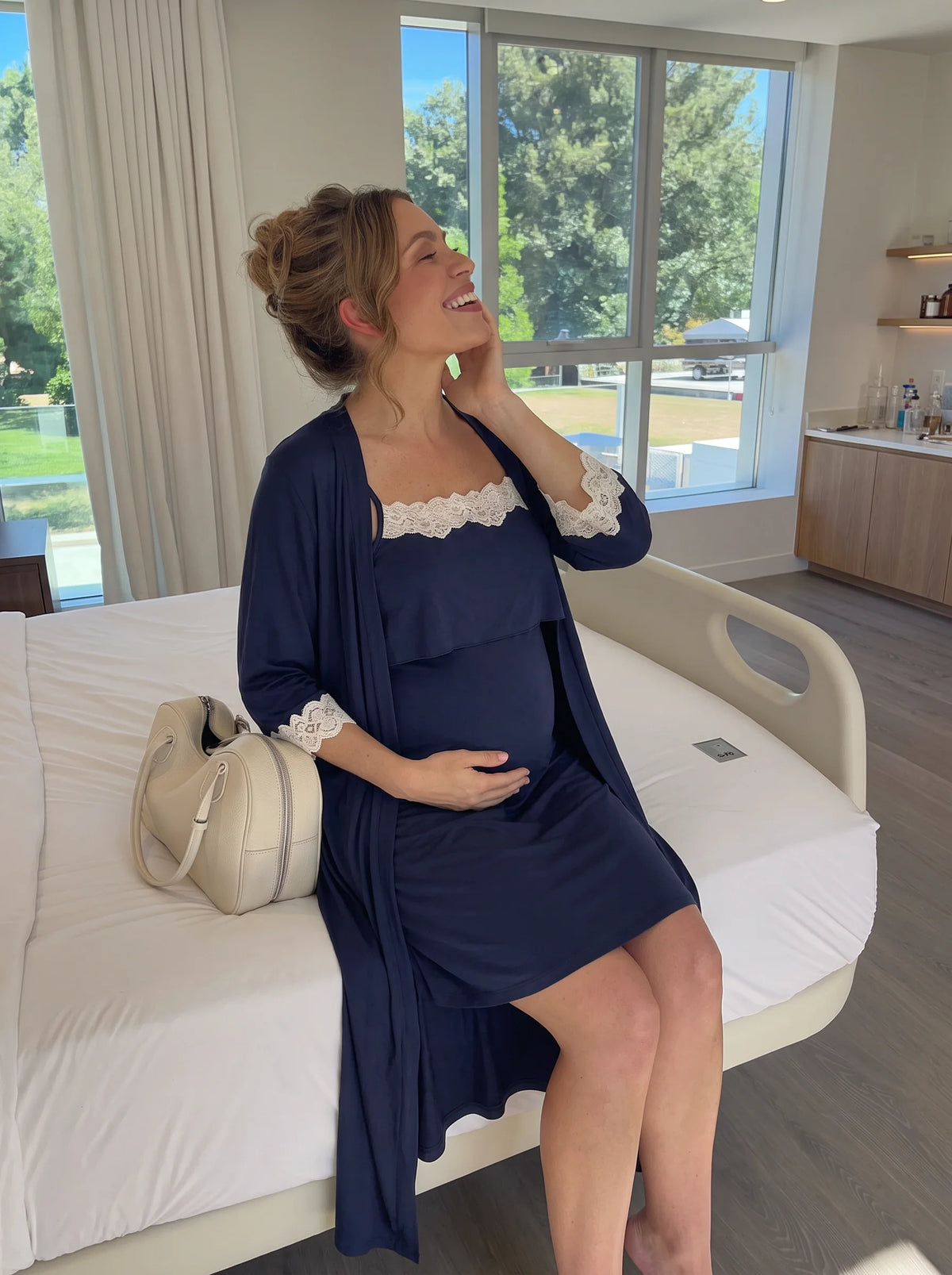 Happy pregnant mom in the navy nightgown and robe in a bright hospital room