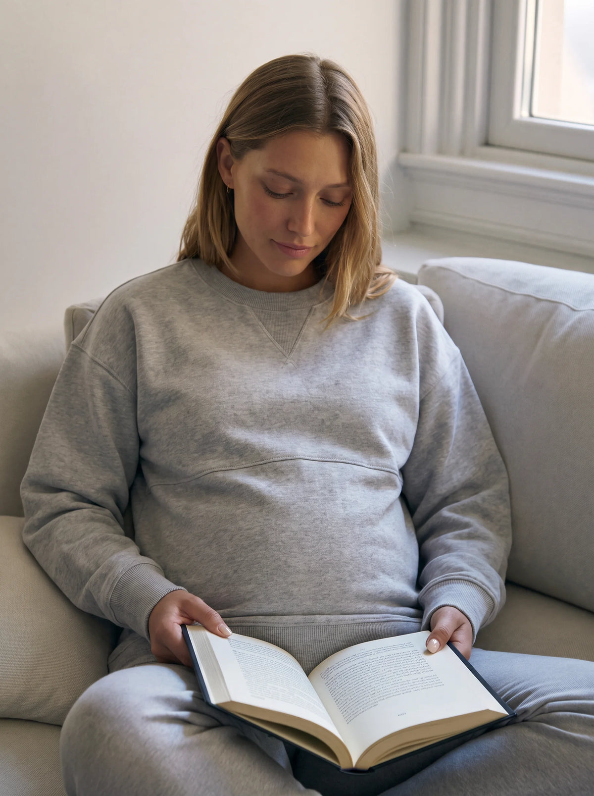 Mom reading on the sofa in gray nursing sweatshirt