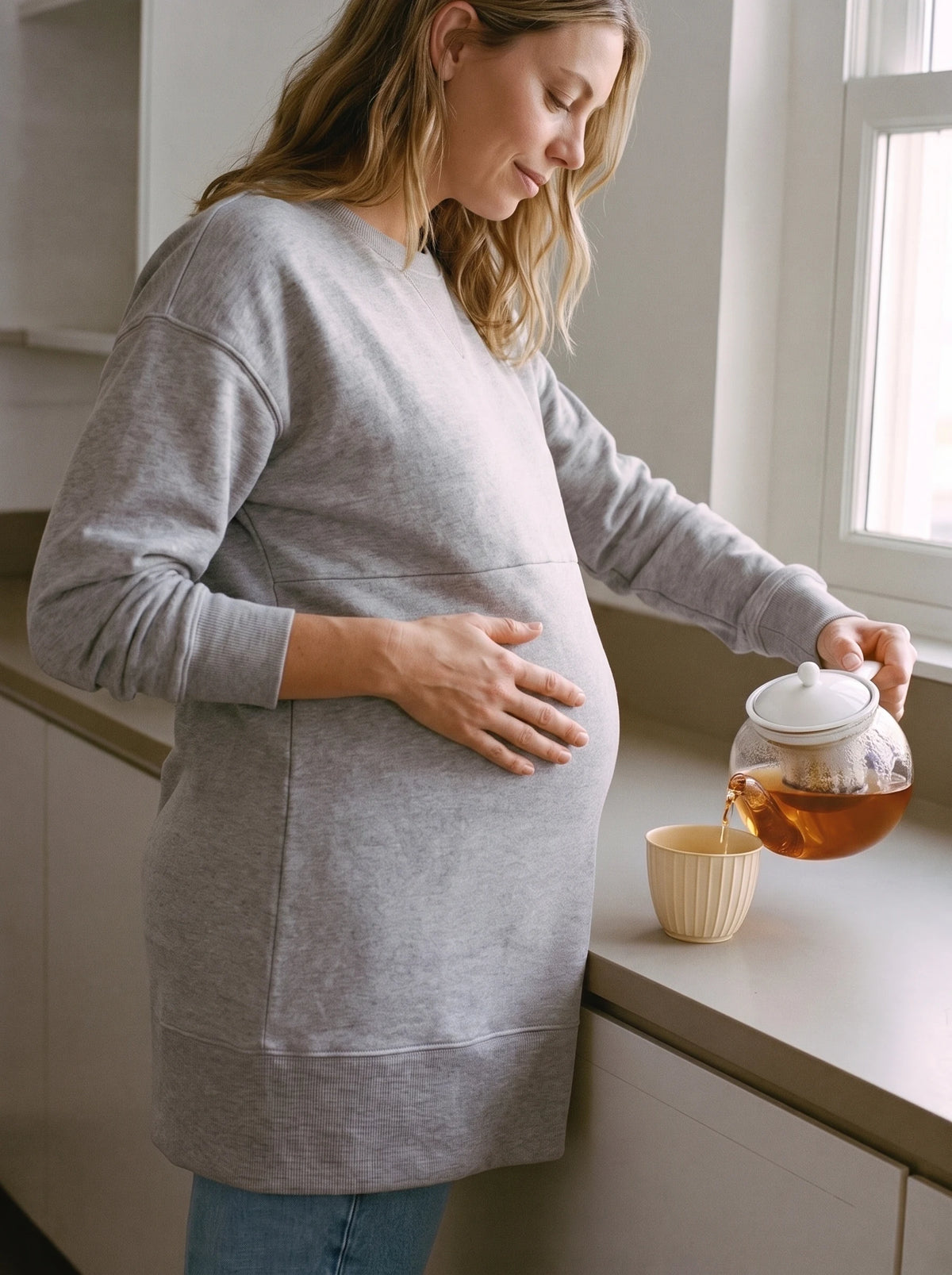 Mom making tea in the kitchen in gray maternity sweatshirt