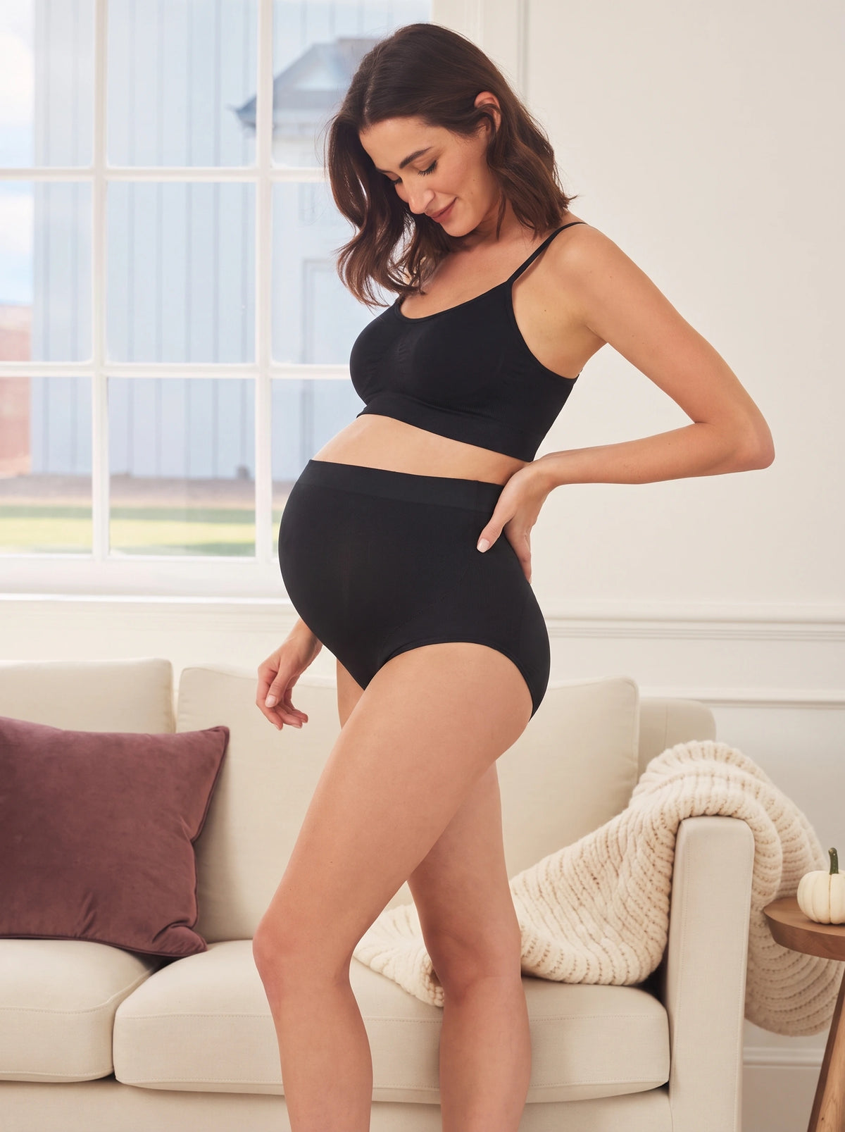 Pregnant mom at home in black Belly Bliss over the bump panties with a matching black bralette