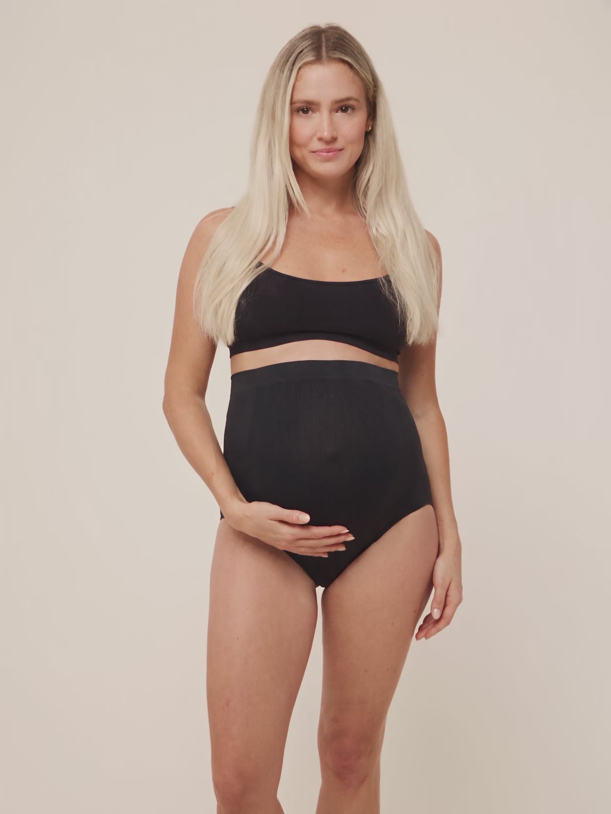 Mom in black Belly Bliss maternity panties turning to show the over the bump fit