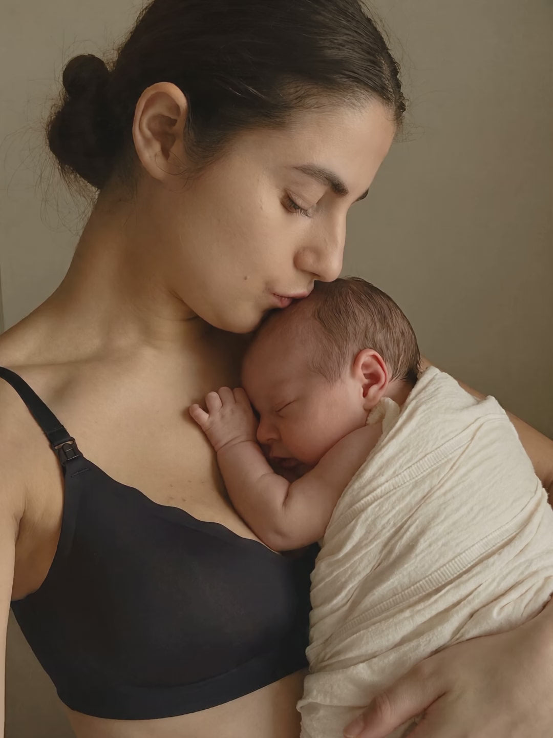 New mom cuddling her newborn in the Aura Comfort Bra in Black